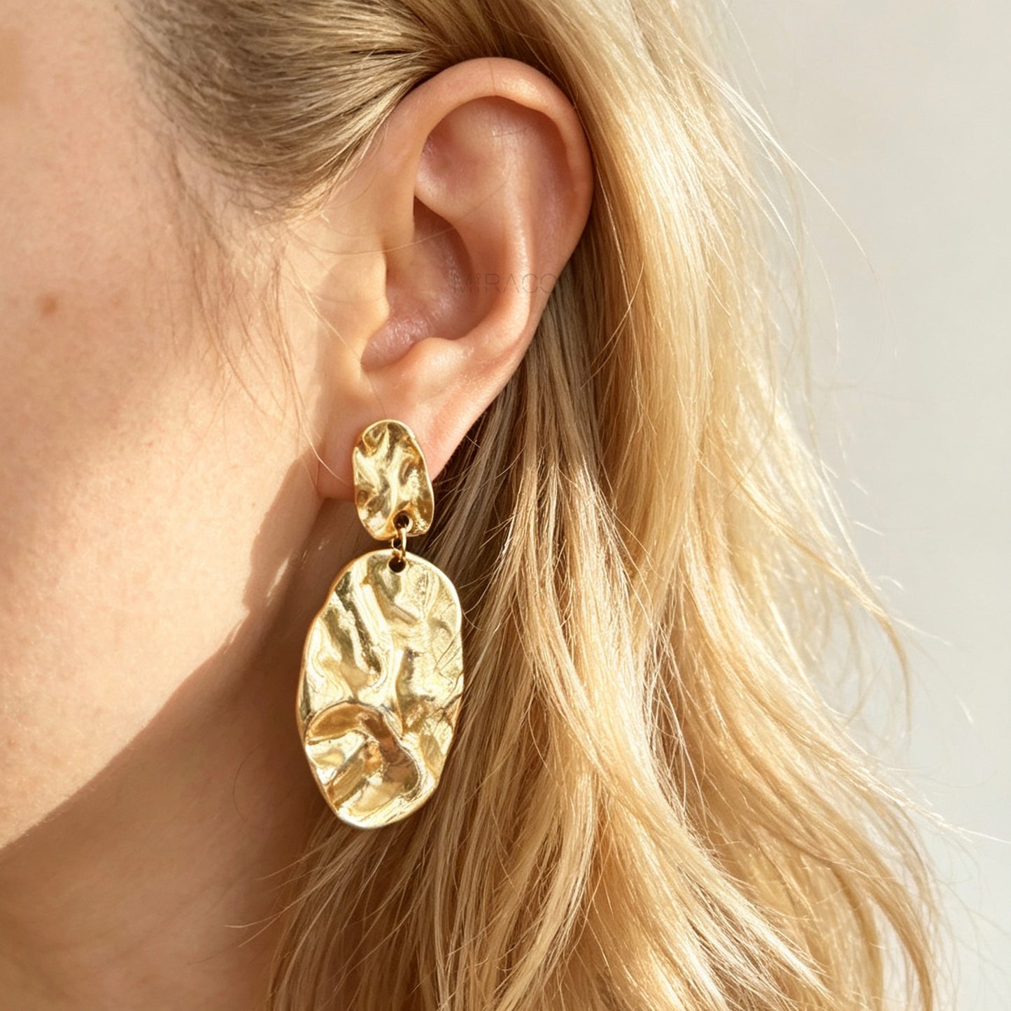 Gold and silver non-pierced statement clip-on earrings with mini clip backs, featuring hammered textured oval metal drop discs.