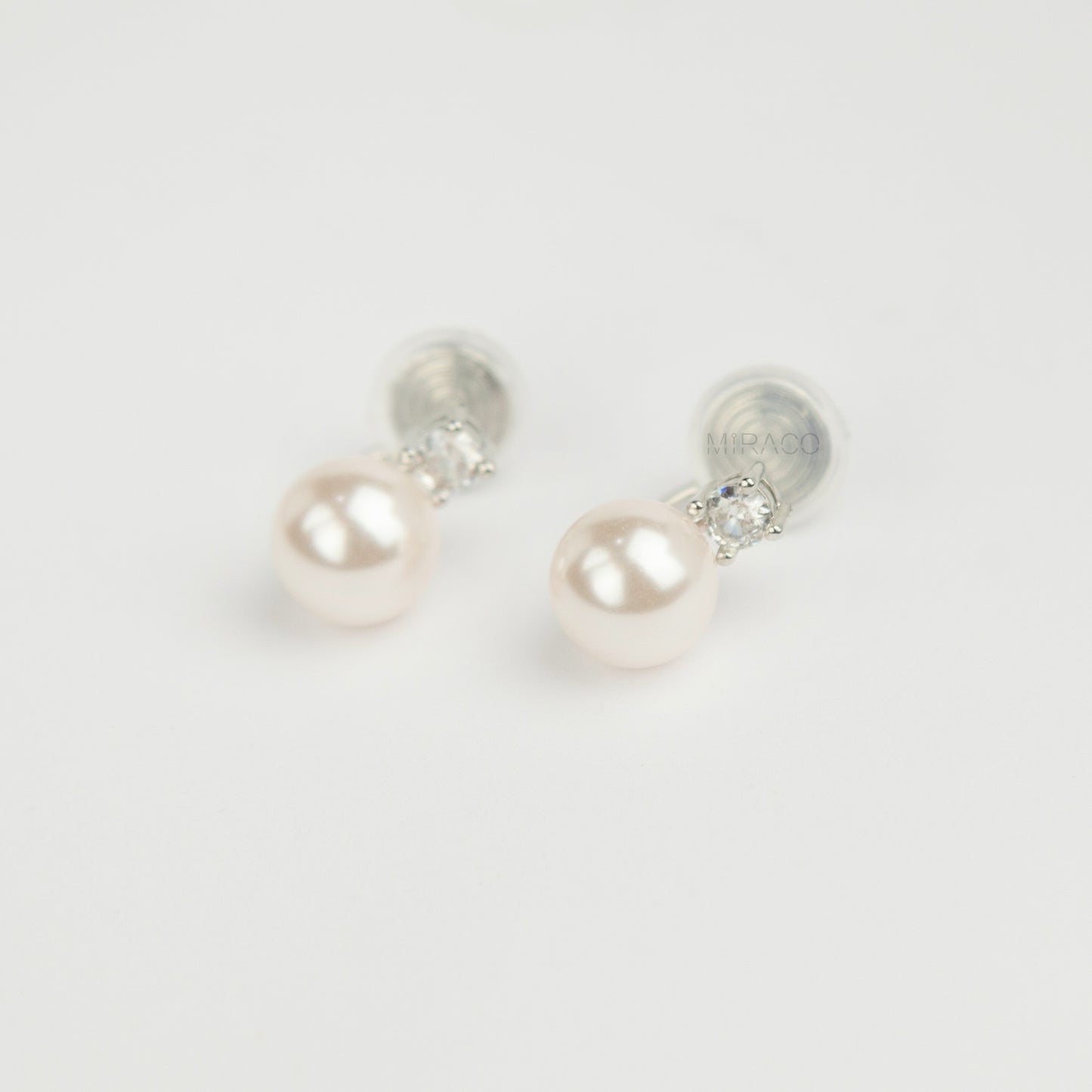 silver-tone non-pierced clip-on earring featuring a round white pearl drop suspended from a sparkling cubic zirconia solitaire with a coil back.