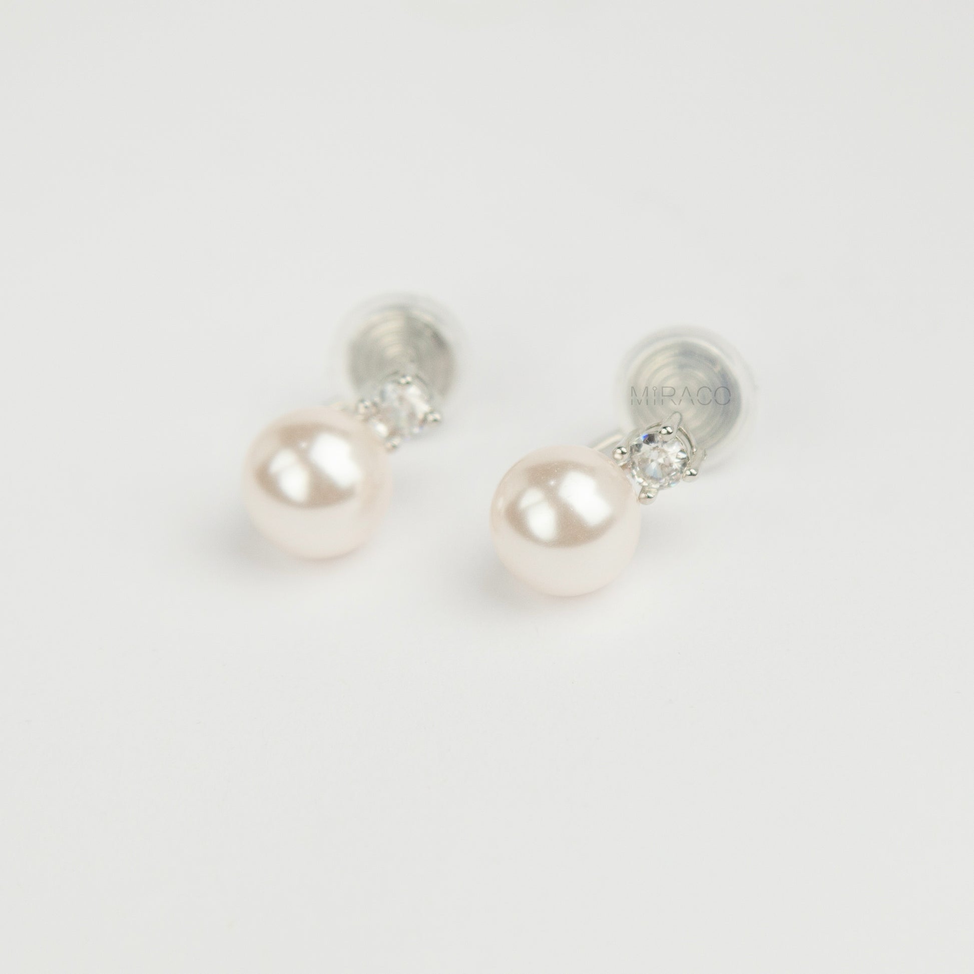 silver-tone non-pierced clip-on earring featuring a round white pearl drop suspended from a sparkling cubic zirconia solitaire with a coil back.