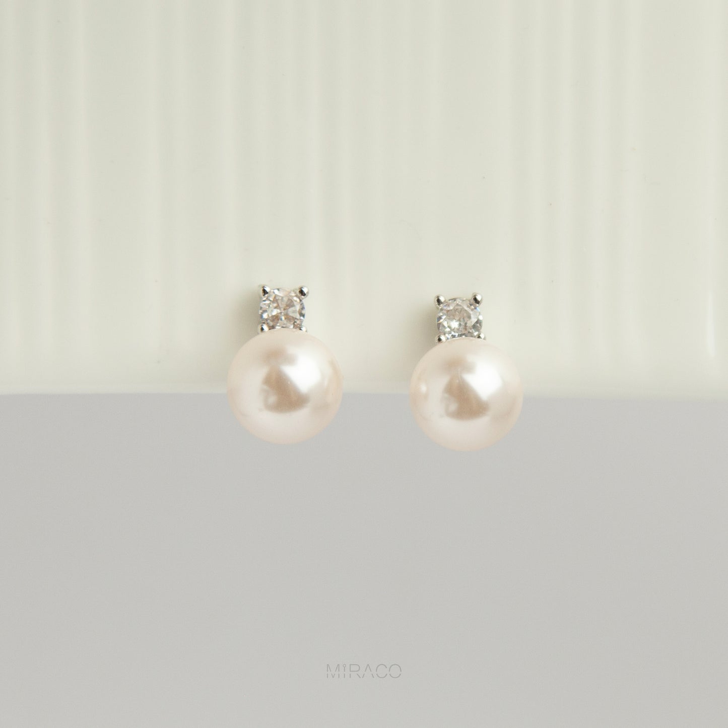 silver-tone non-pierced clip-on earring featuring a round white pearl drop suspended from a sparkling cubic zirconia solitaire with a coil back.