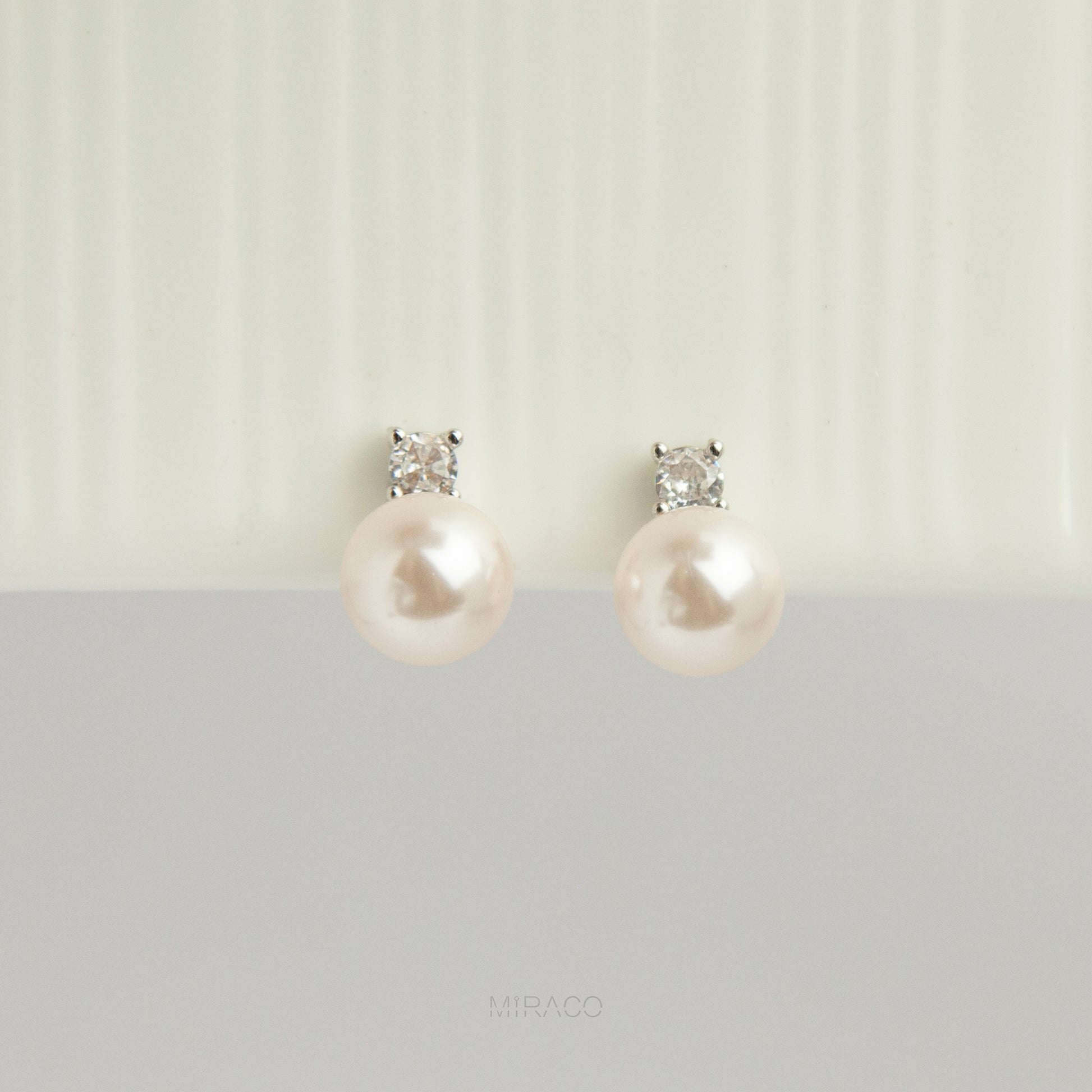 silver-tone non-pierced clip-on earring featuring a round white pearl drop suspended from a sparkling cubic zirconia solitaire with a coil back.