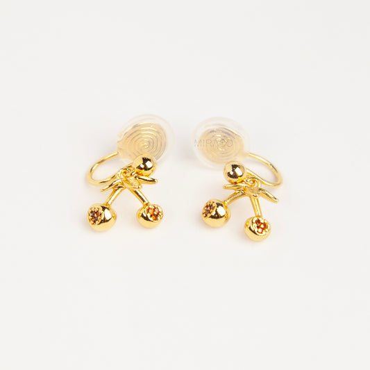 Pair of polished gold-toned double cherry clip-on earrings with amber rhinestone accents and comfortable silicone-backed spiral coil clips.