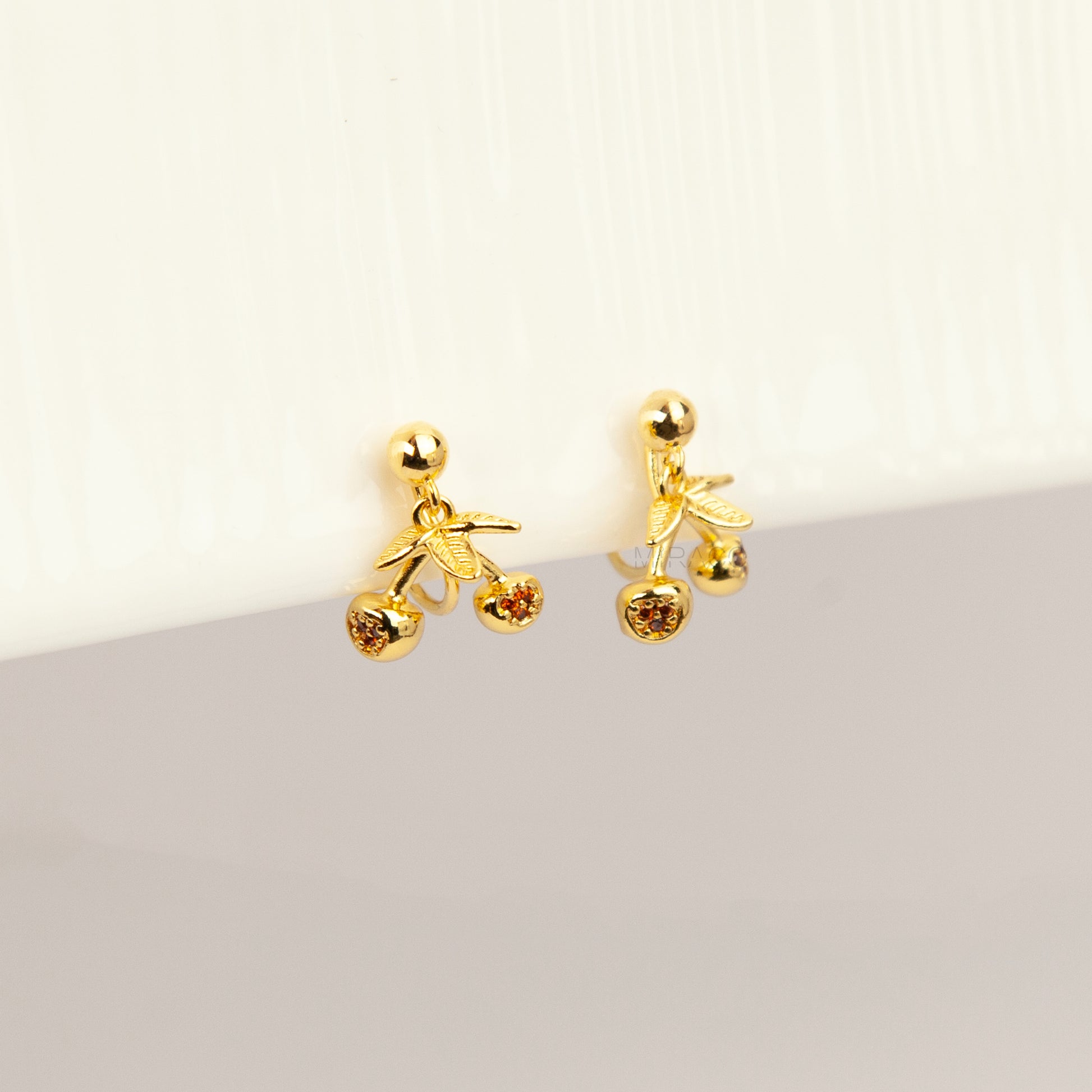 gold-toned double cherry clip-on earrings with amber rhinestone accents and comfortable silicone-backed spiral coil clips.