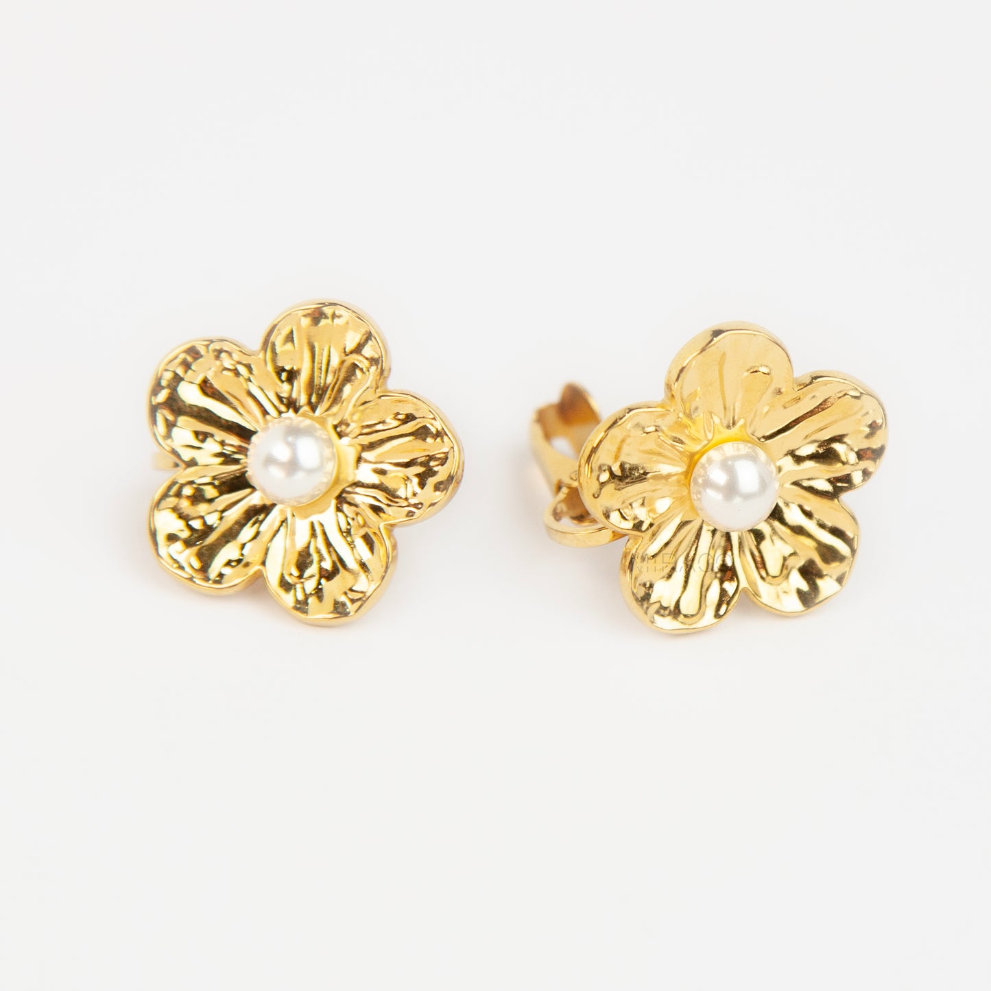 Pair of gold-toned non-pierced flower clip-on stud earrings with textured petals, white faux pearl center, and paddle back clip mechanism.