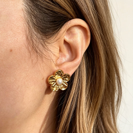 Pair of gold-toned non-pierced flower clip-on stud earrings with textured petals, white faux pearl center, and paddle back clip mechanism.