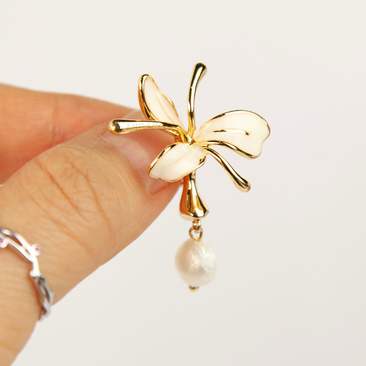 Pair of gold-toned non-pierced clip-on earrings featuring cream enamel floral petals with dangling genuine freshwater pearls and spiral coil backs.