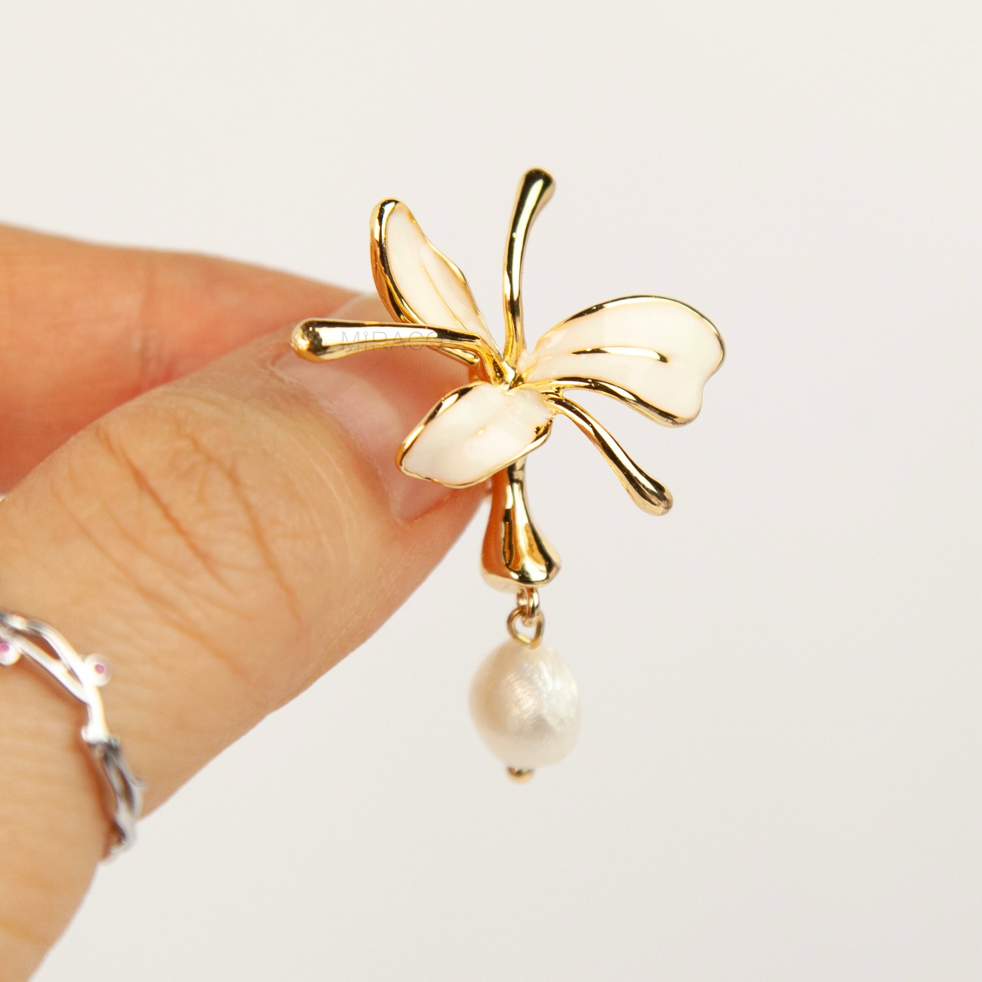 Pair of gold-toned non-pierced clip-on earrings featuring cream enamel floral petals with dangling genuine freshwater pearls and spiral coil backs.