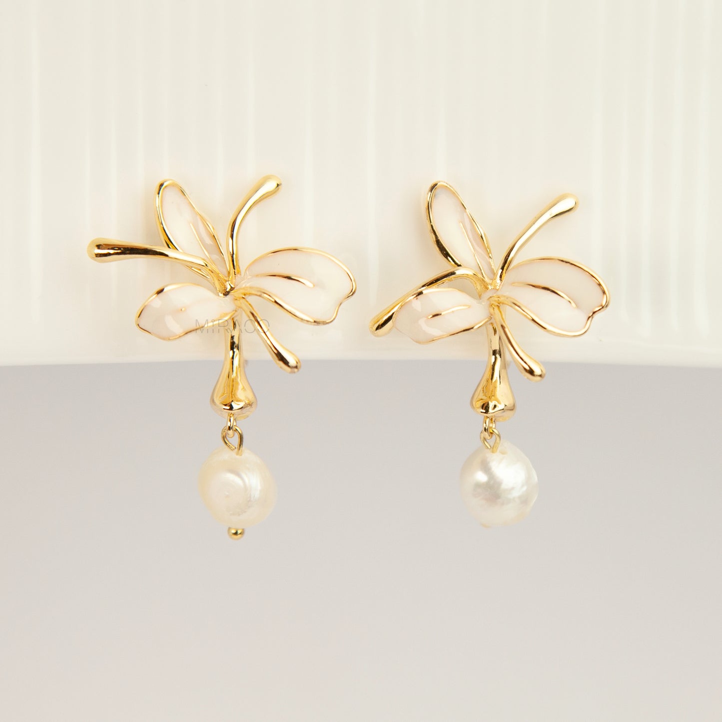 Pair of gold-toned non-pierced clip-on earrings featuring cream enamel floral petals with dangling genuine freshwater pearls and spiral coil backs.