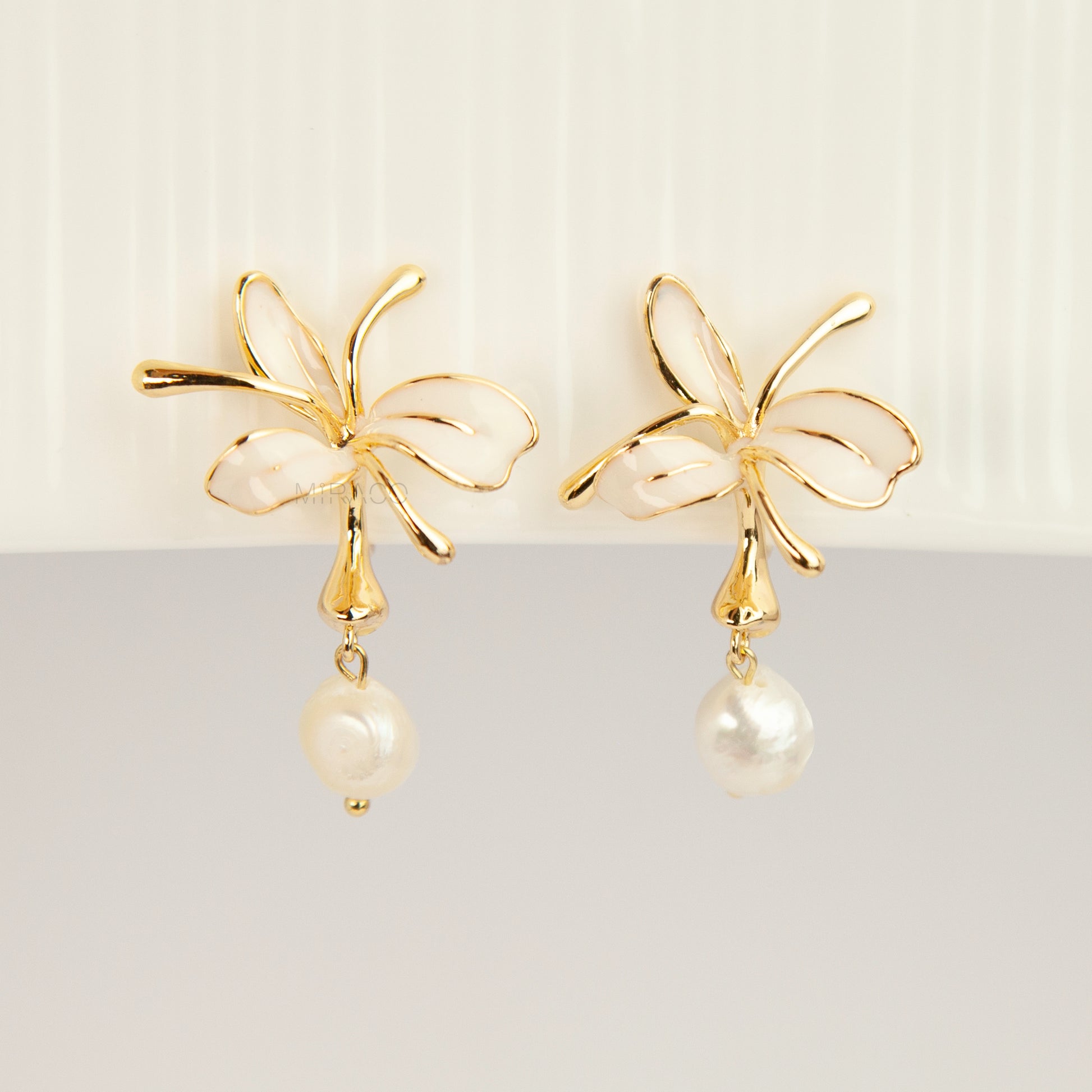 Pair of gold-toned non-pierced clip-on earrings featuring cream enamel floral petals with dangling genuine freshwater pearls and spiral coil backs.
