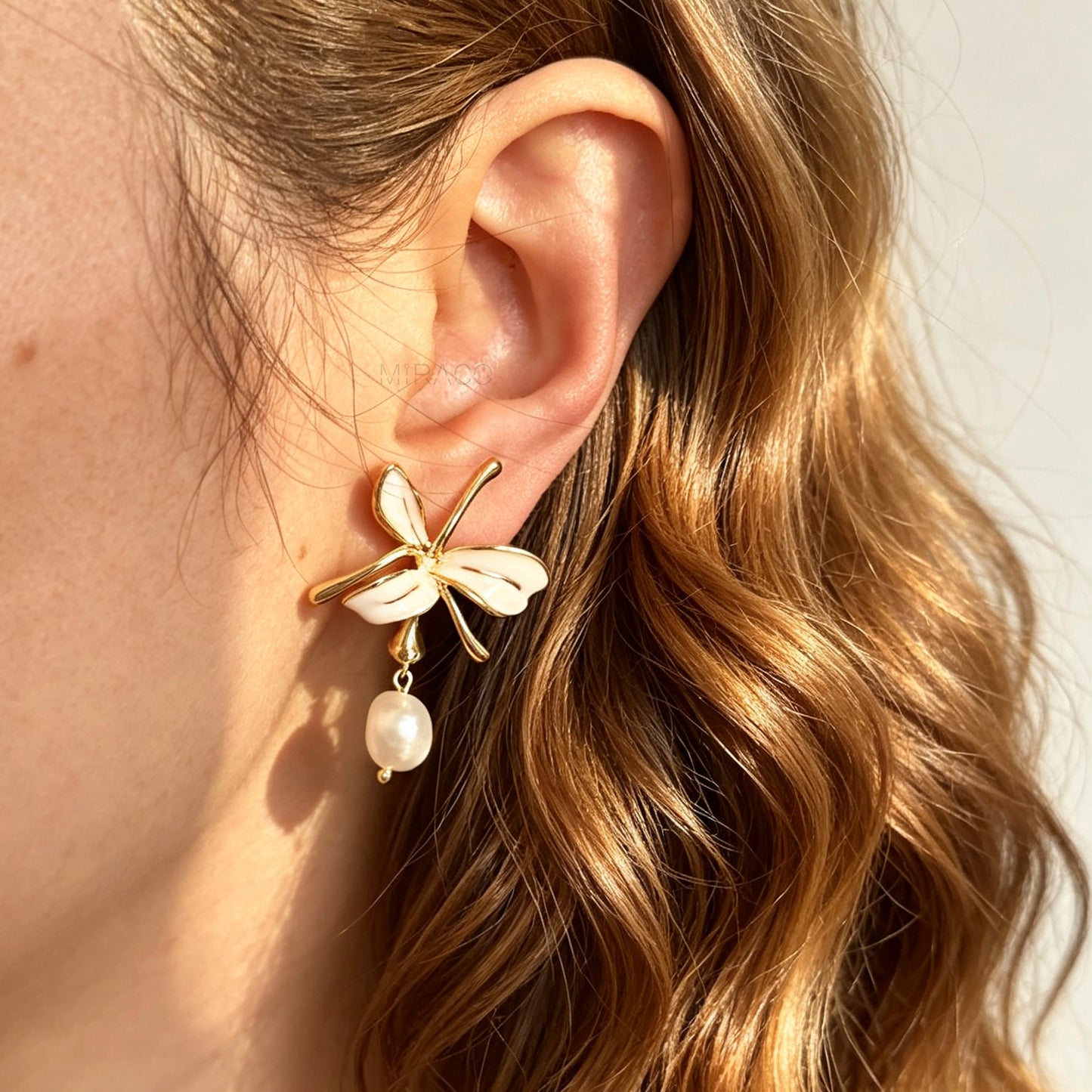 Pair of gold-toned non-pierced clip-on earrings featuring cream enamel floral petals with dangling genuine freshwater pearls and spiral coil backs.
