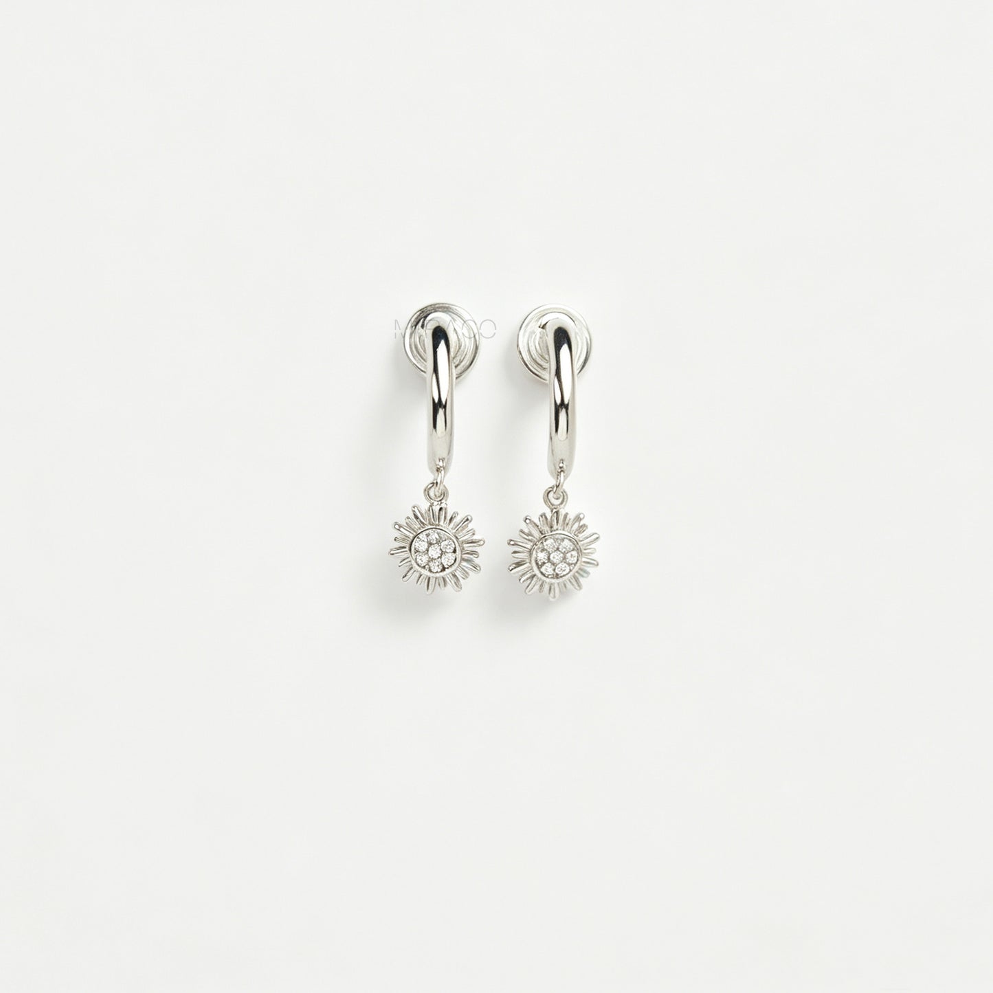 Pair of silver-toned non-pierced clip-on hoop earrings featuring dangling pave crystal sunburst charms and silicone-padded spiral coil backs.