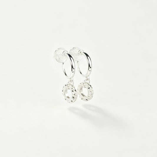 Pair of silver-toned non-pierced clip-on hoop earrings with dangling textured open circle discs and clear silicone spiral coil backs.