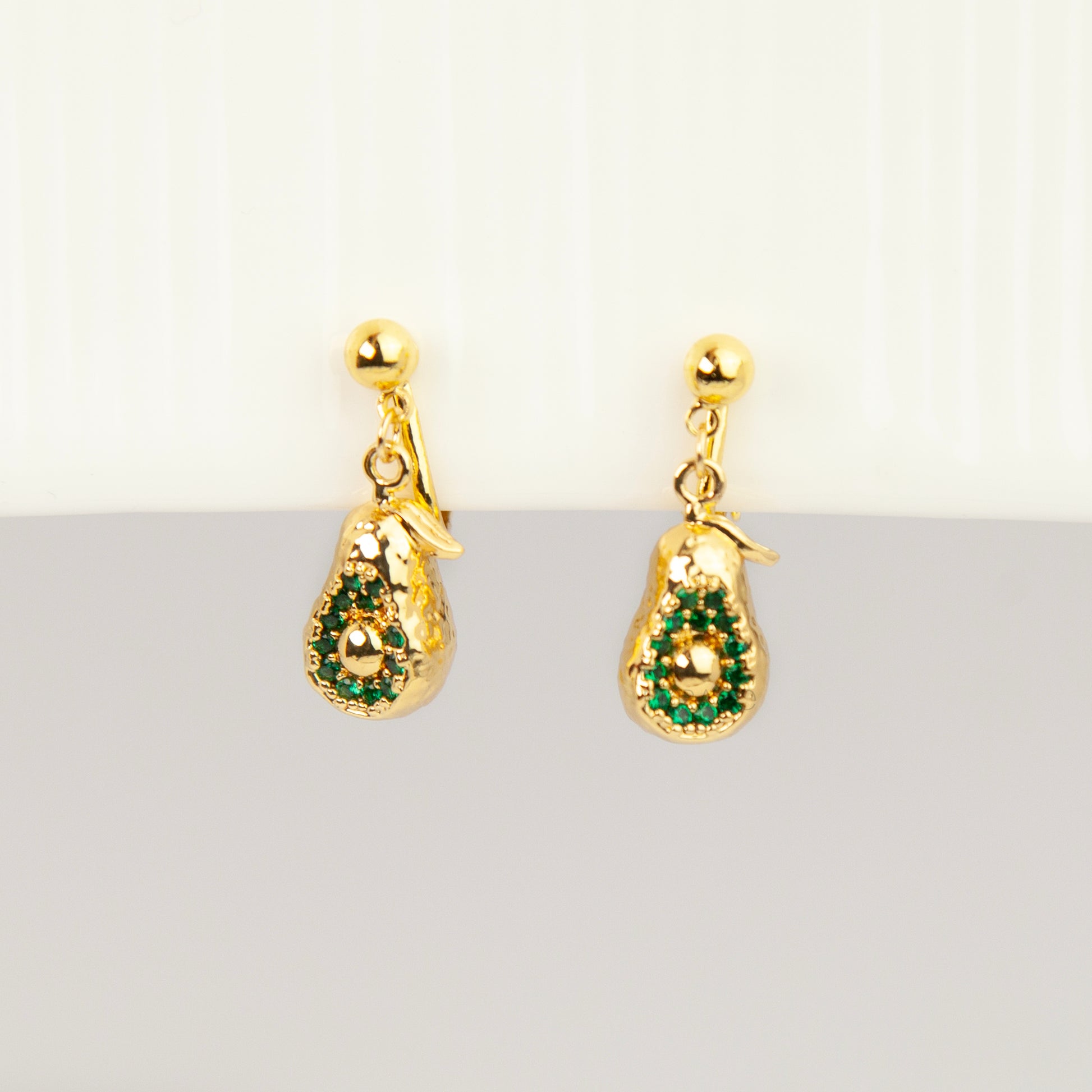 Pair of gold-toned non-pierced avocado clip-on drop earrings with green crystal accents and adjustable screw-back mechanisms.