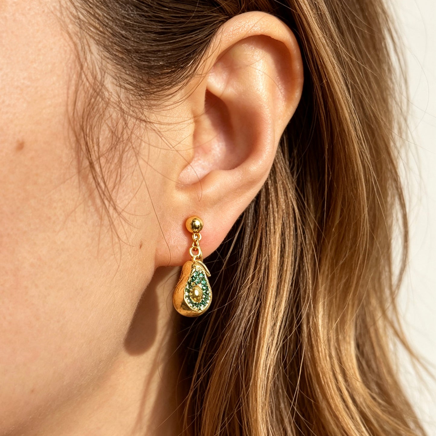 Pair of gold-toned non-pierced avocado clip-on drop earrings with green crystal accents and adjustable screw-back mechanisms.