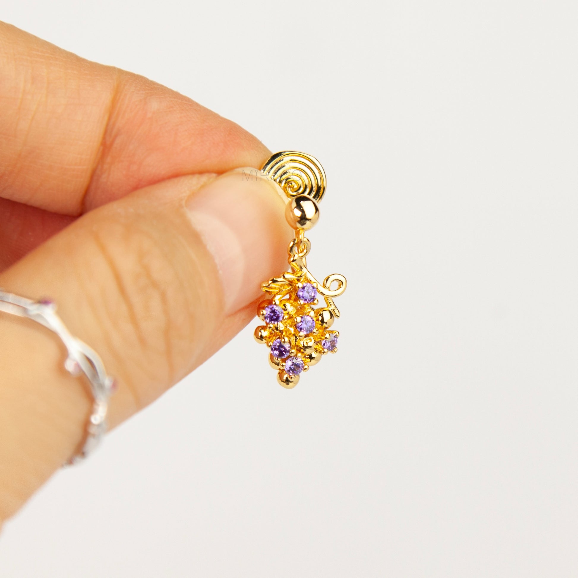 Pair of gold grape cluster clip-on drop earrings encrusted with purple crystals featuring pain-free coil backs for non-pierced ears on a white background.