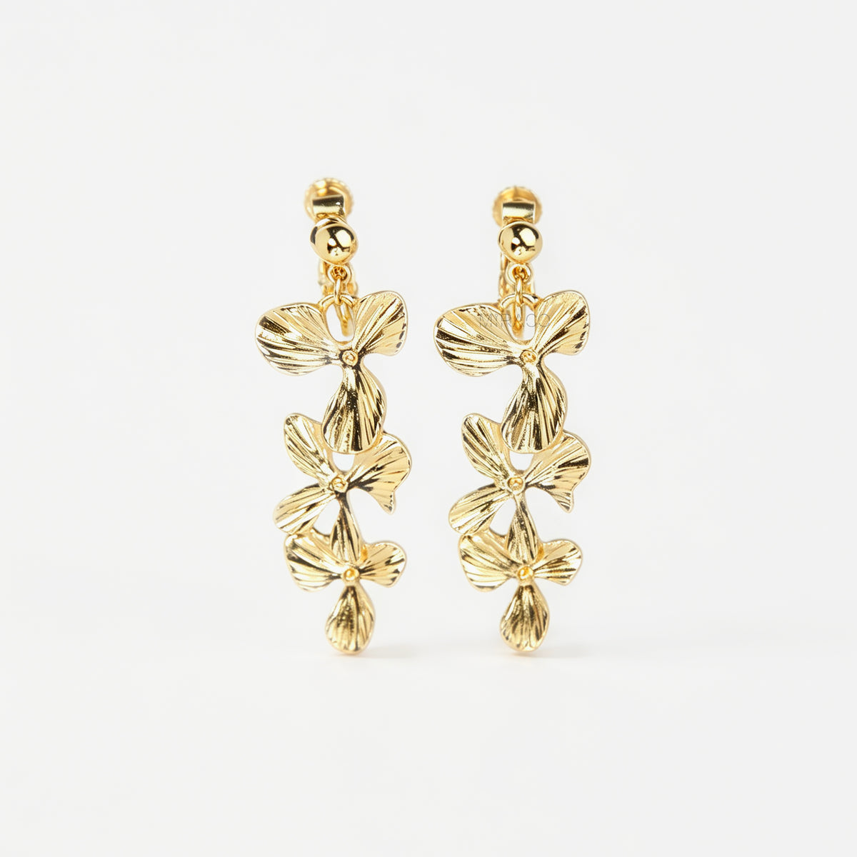 Pair of gold textured floral clip-on earrings with adjustable screw-back closures showing cascading layered flower petals on a clean neutral background
