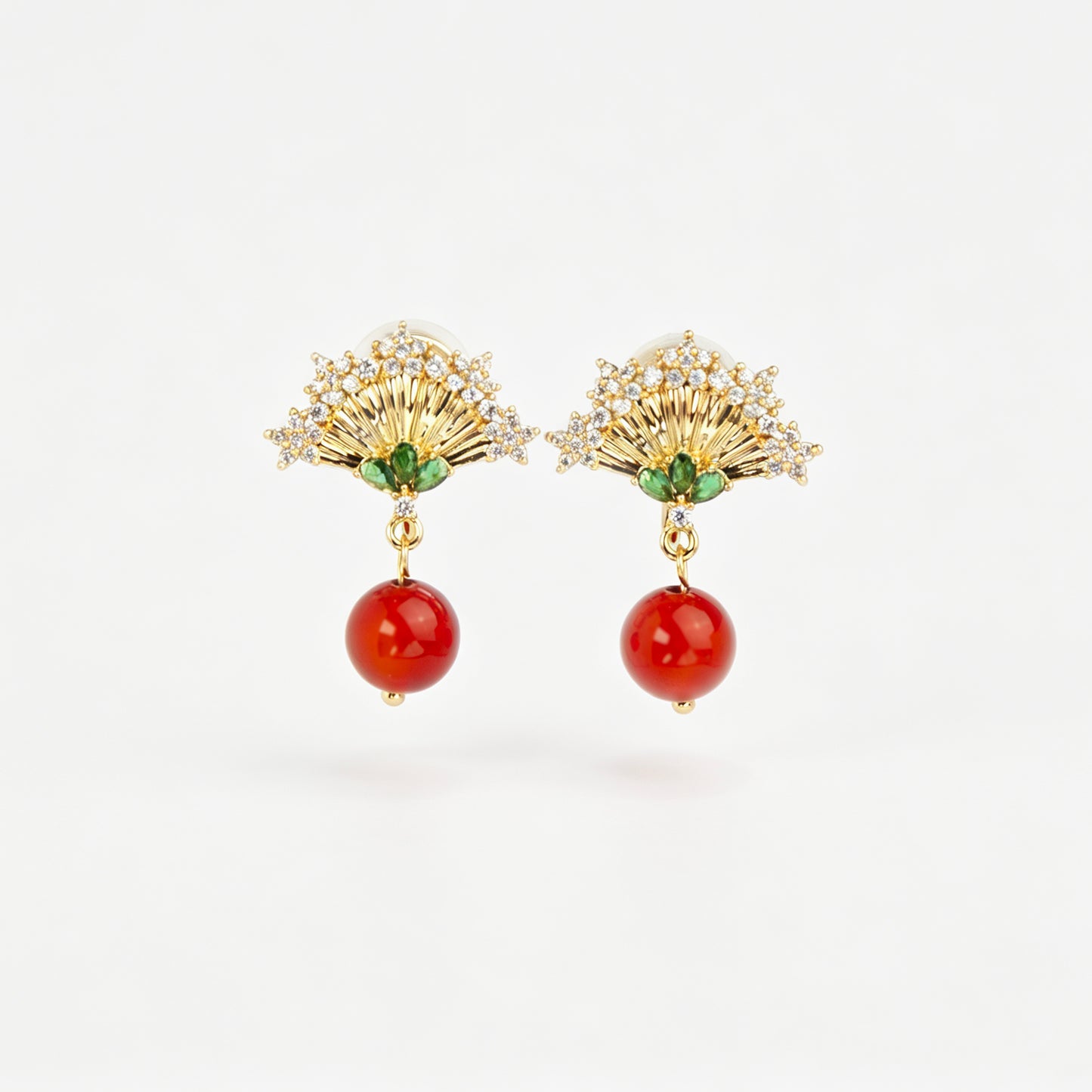 Gold Art Deco fan-shaped clip-on earrings with green crystal accents, pavé CZ trim, and hanging red agate bead drops 
