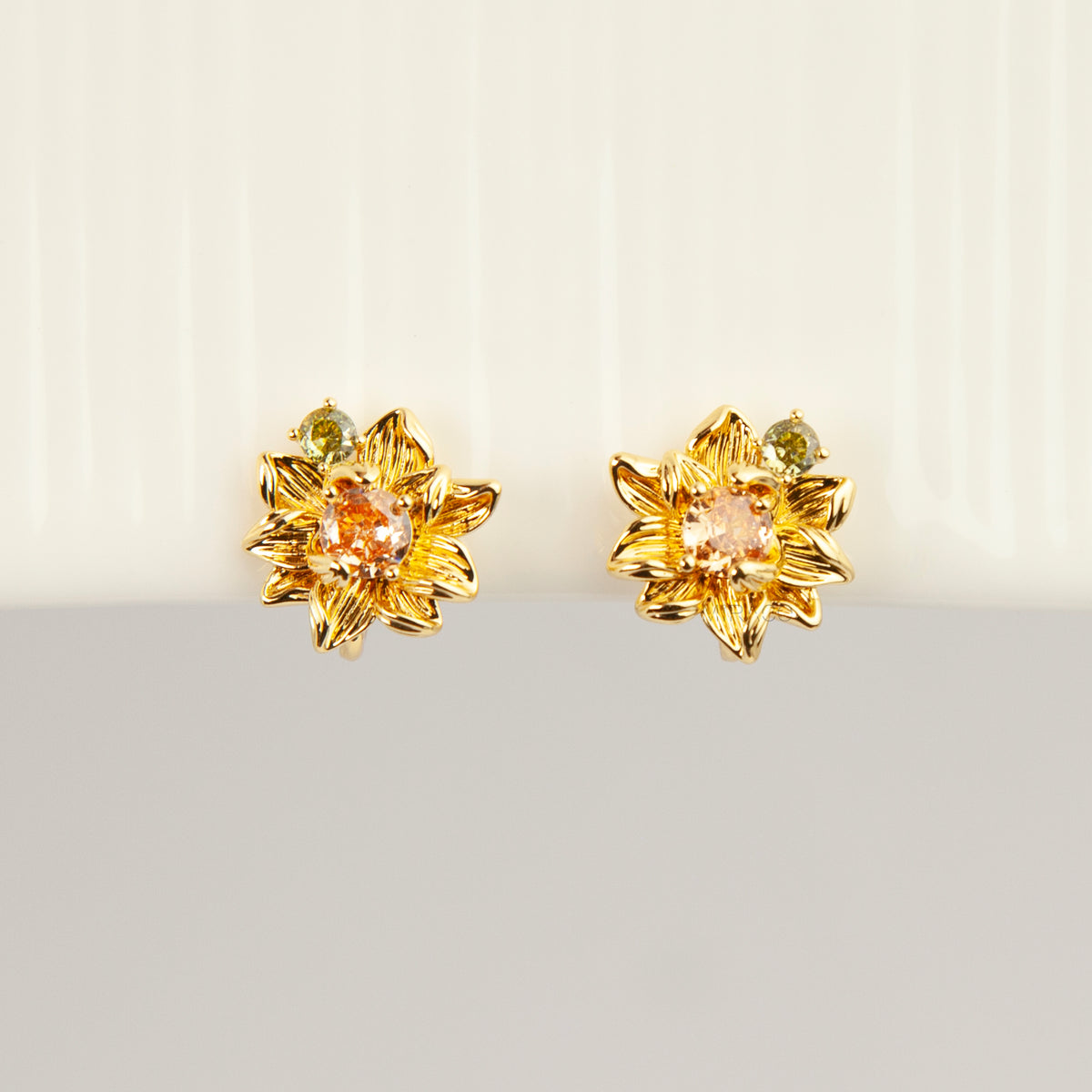 Pair of detailed gold sunflower clip-on stud earrings with amber crystal centers and olive green stone accents