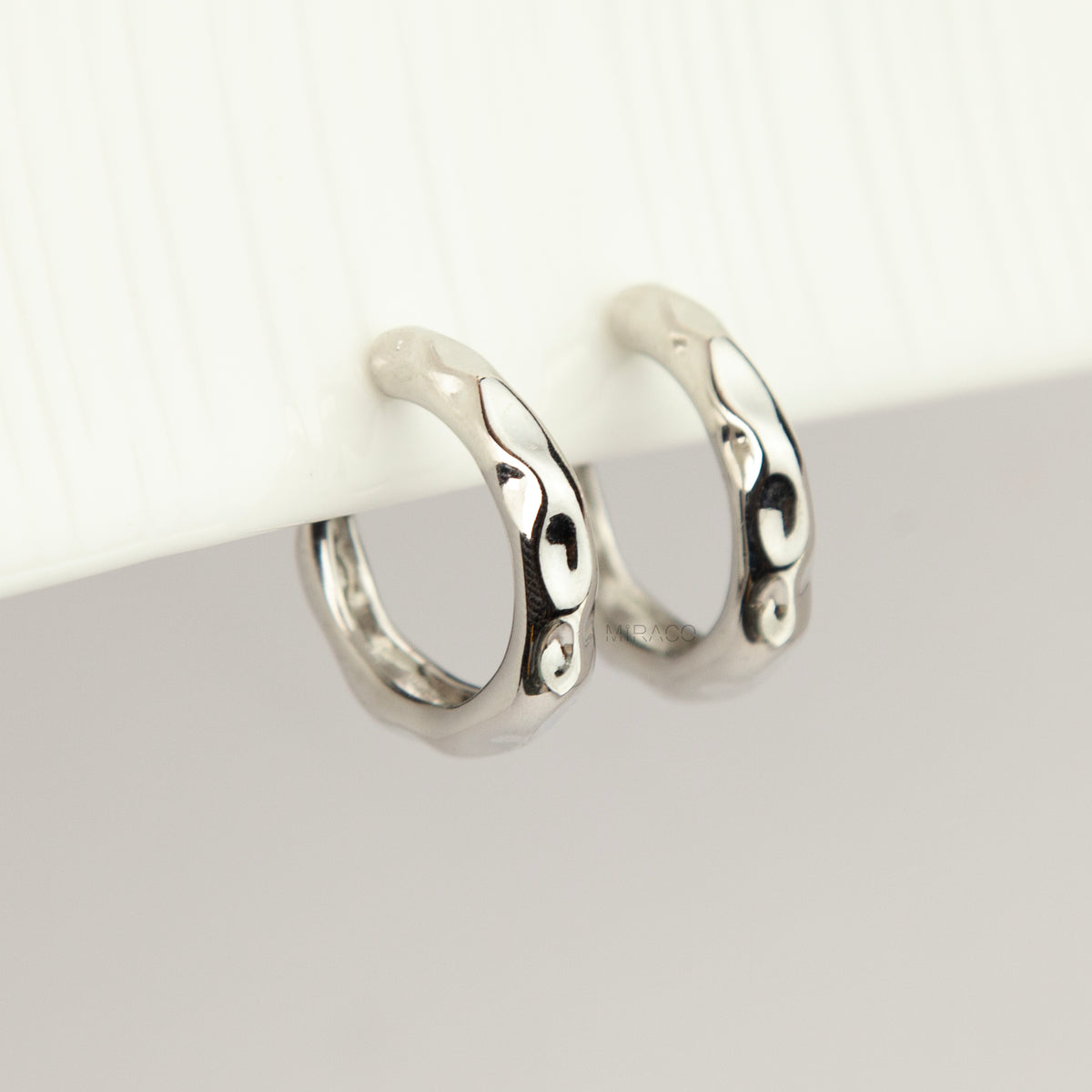 Silver chunky molten clip-on hoop earrings with adjustable screw-back closures featuring an organic wavy textured finish