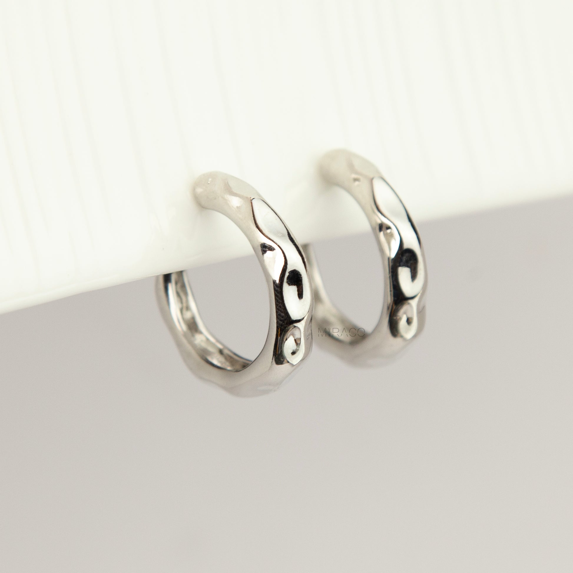 Silver chunky molten clip-on hoop earrings with adjustable screw-back closures featuring an organic wavy textured finish