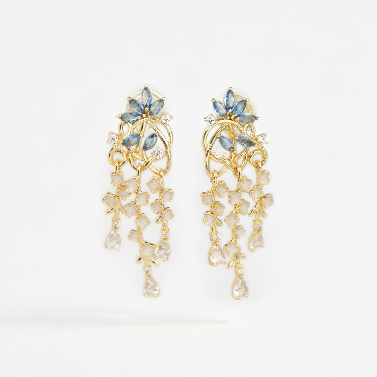 Gold coil-back clip-on chandelier earrings featuring blue marquise petals and cascading white flower dangles with teardrop crystals