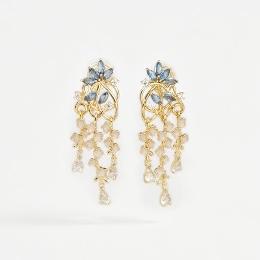 Gold coil-back clip-on chandelier earrings featuring blue marquise petals and cascading white flower dangles with teardrop crystals