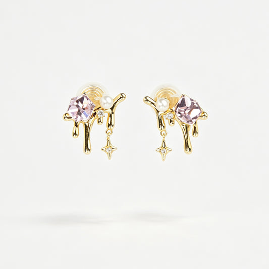 Gold coil-back clip-on earrings featuring a molten liquid drip design with a geometric pink crystal, white pearl, and dangling starburst charm.