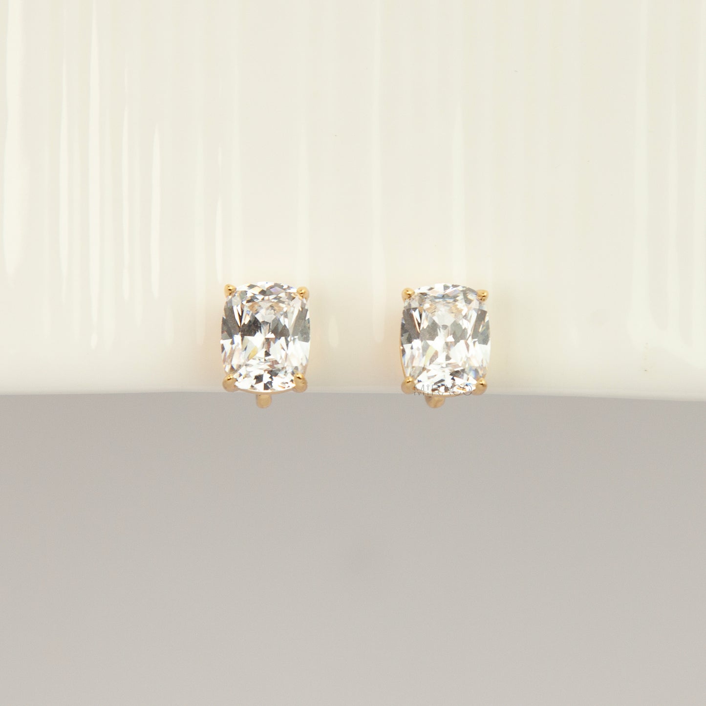 Gold-tone clip-on stud earrings set with large cushion-cut clear crystals and round silicone backs 