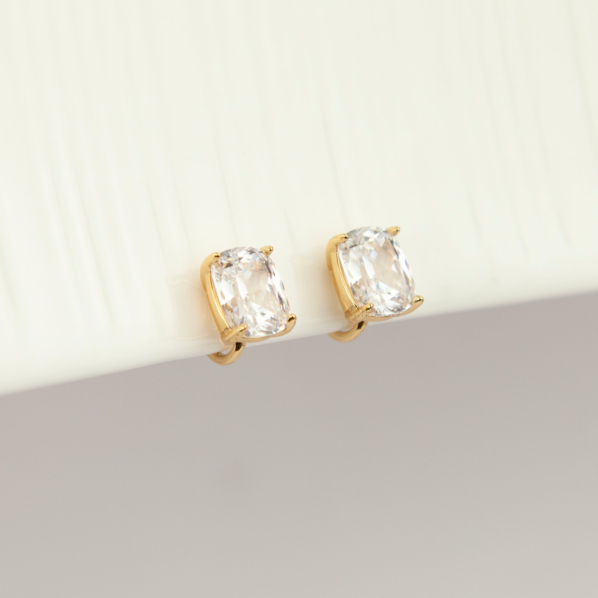 Gold-tone clip-on stud earrings set with large cushion-cut clear crystals and round silicone backs 