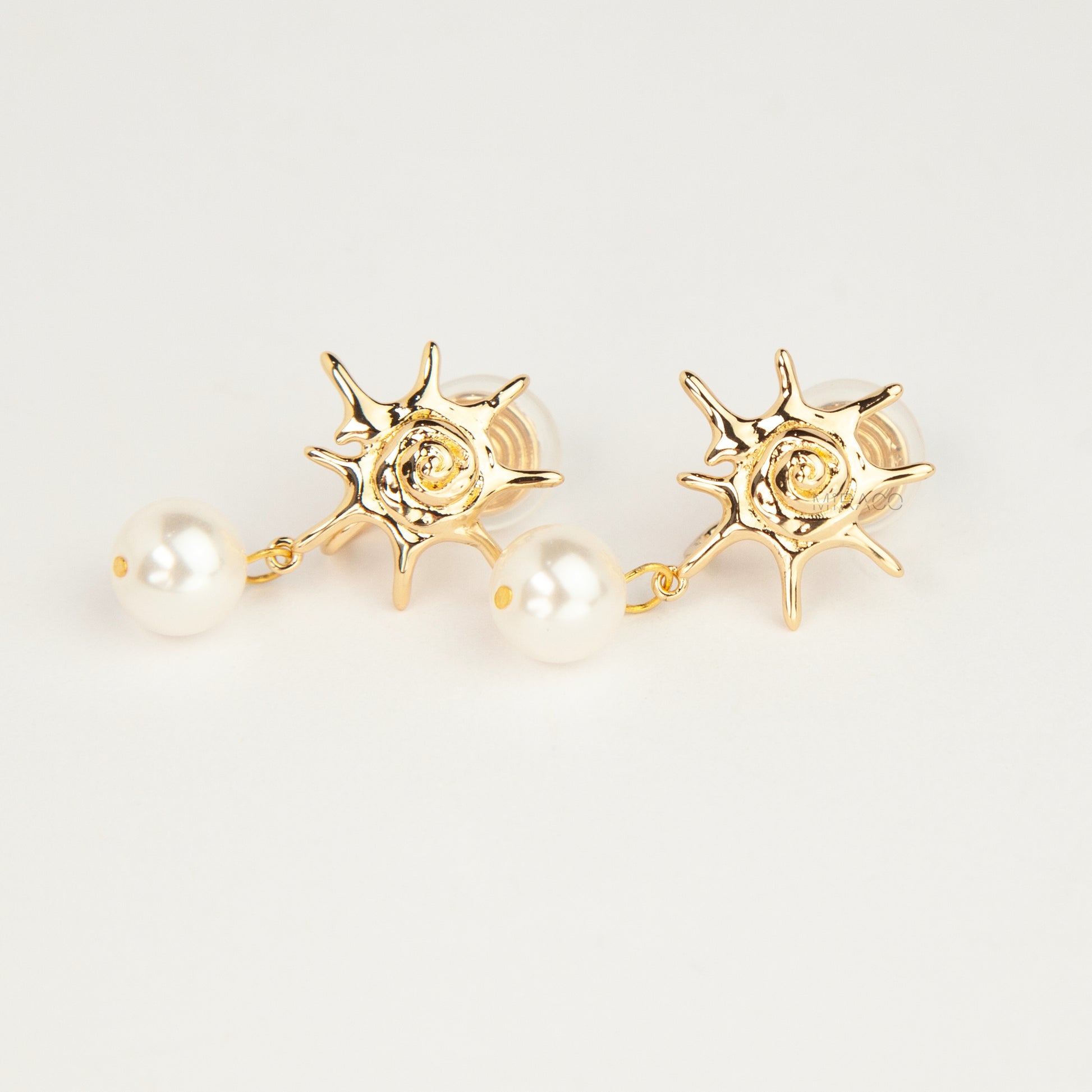 Gold coil-back clip-on earrings with a swirled sunburst star motif and a dangling white pearl