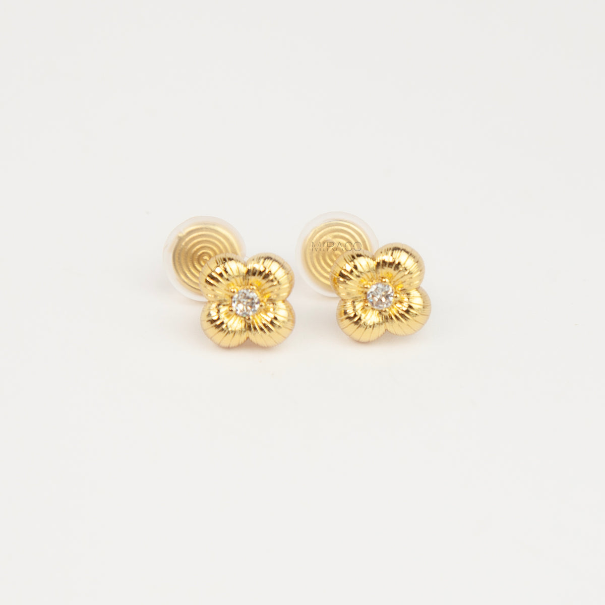 Textured gold clover-shaped floral clip-on stud earrings set with a round central crystal and a coil-back closure.