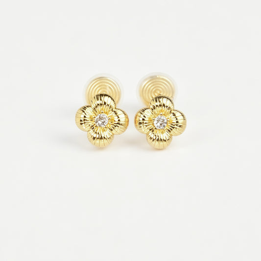 Textured gold clover-shaped floral clip-on stud earrings set with a round central crystal and a coil-back closure.