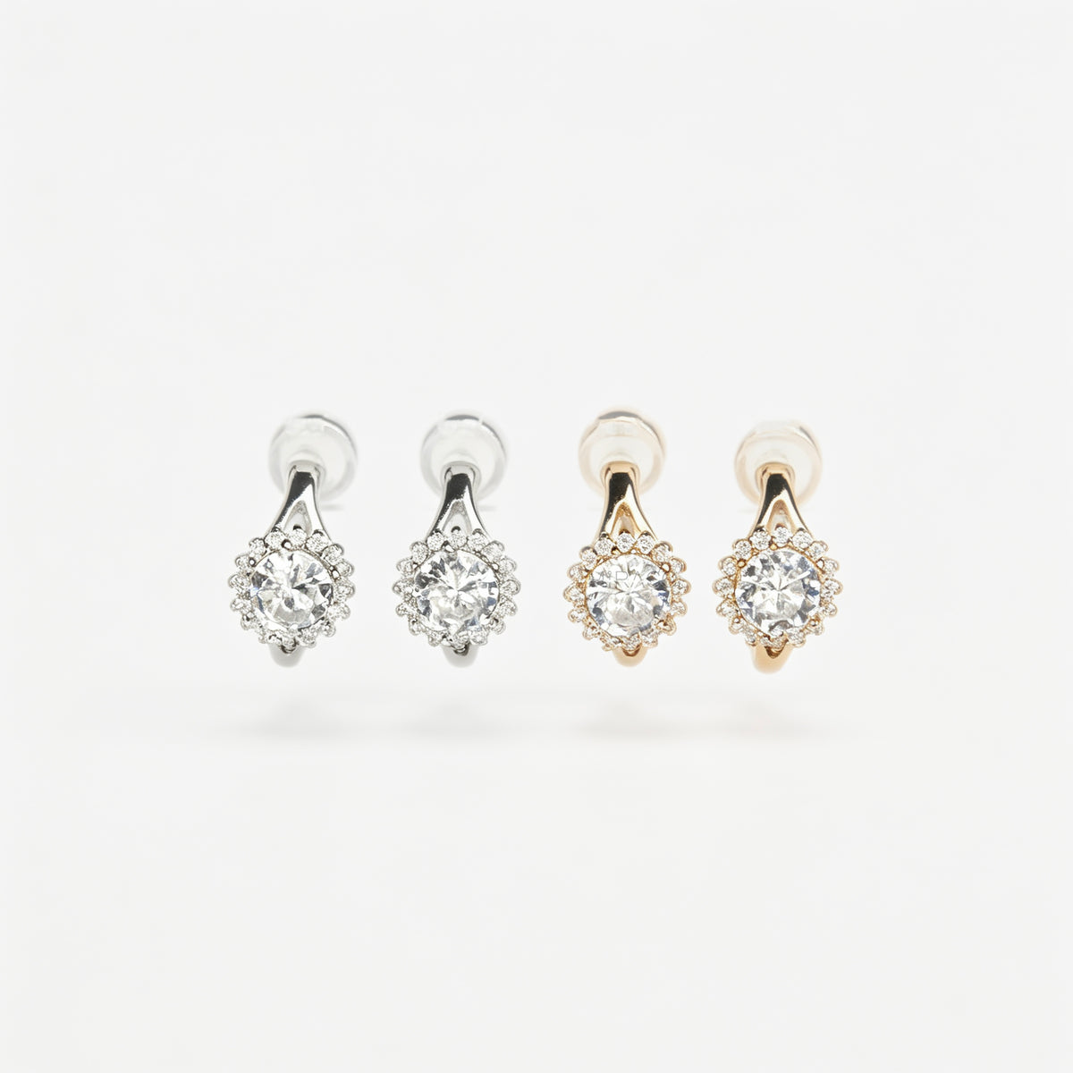 Gold and silver halo crystal coil-back clip-on huggie earrings set with a round solitaire gem surrounded by pave stones.
