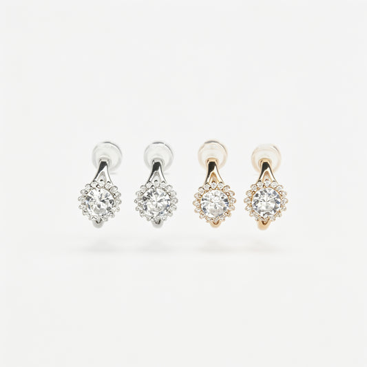 Gold and silver halo crystal coil-back clip-on huggie earrings set with a round solitaire gem surrounded by pave stones.