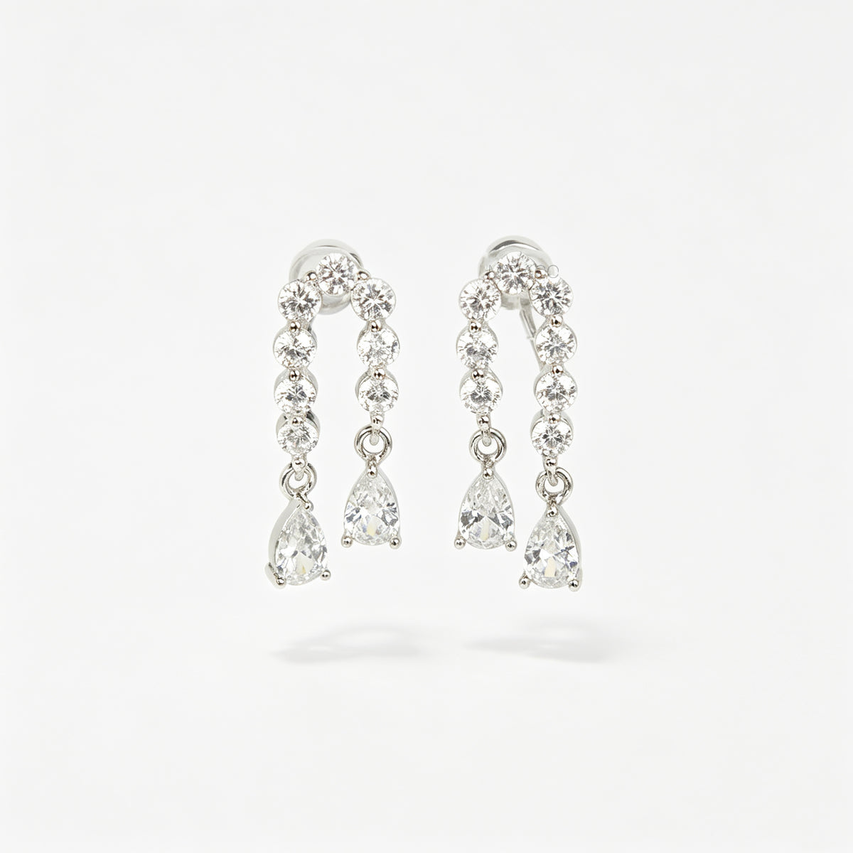 Silver non-pierced clip-on arch earrings with round silicone backs, paved with round cubic zirconia and finished with dangling teardrop crystal gems