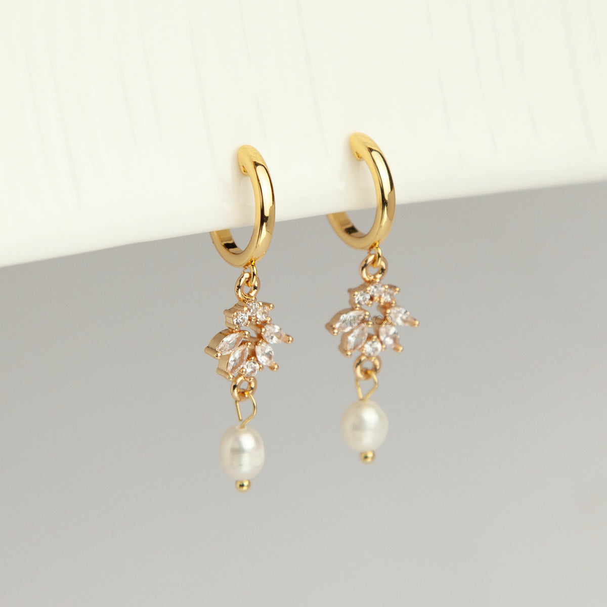 Gold screw-back clip-on hoop earrings with a sparkling cubic zirconia marquise sunburst charm and hanging white pearl drop