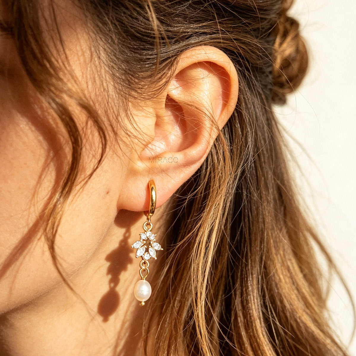 Gold screw-back clip-on hoop earrings with a sparkling cubic zirconia marquise sunburst charm and hanging white pearl drop