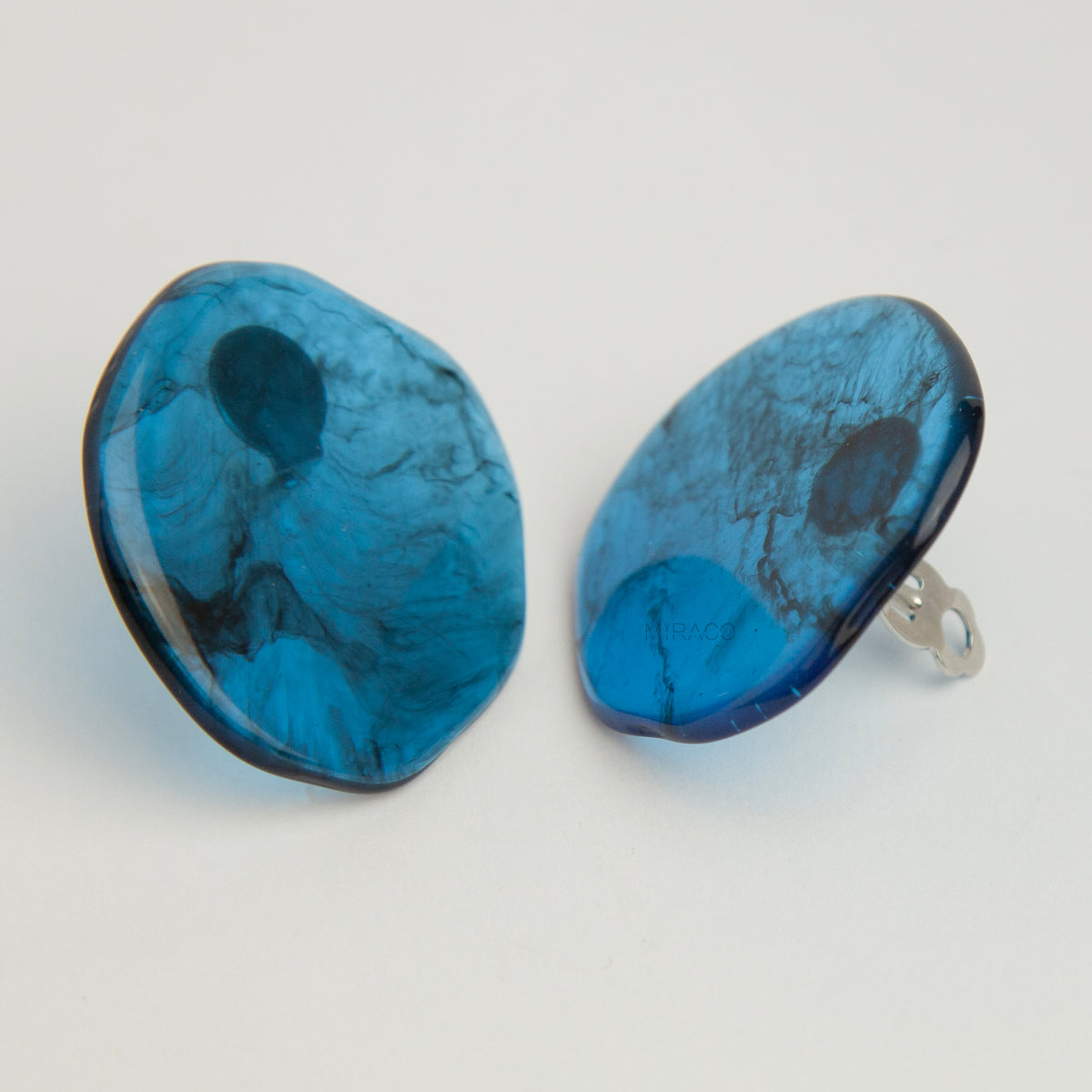 Large organic oval clip-on earring featuring a blue and black marbled resin design