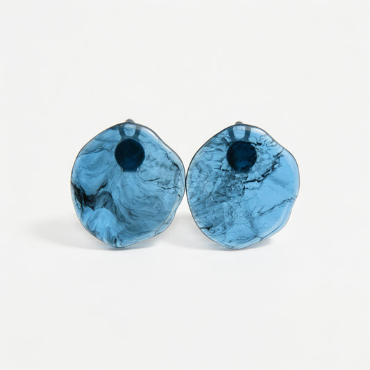 Large organic oval clip-on earring featuring a blue and black marbled resin design