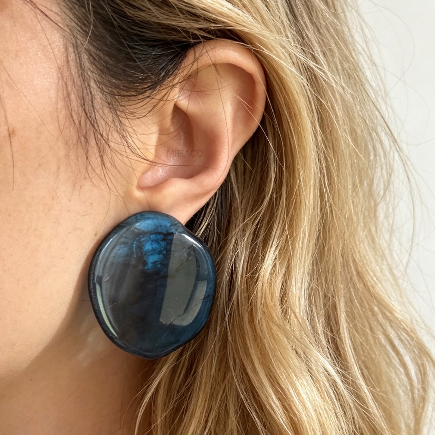 Large organic oval clip-on earring featuring a blue and black marbled resin design