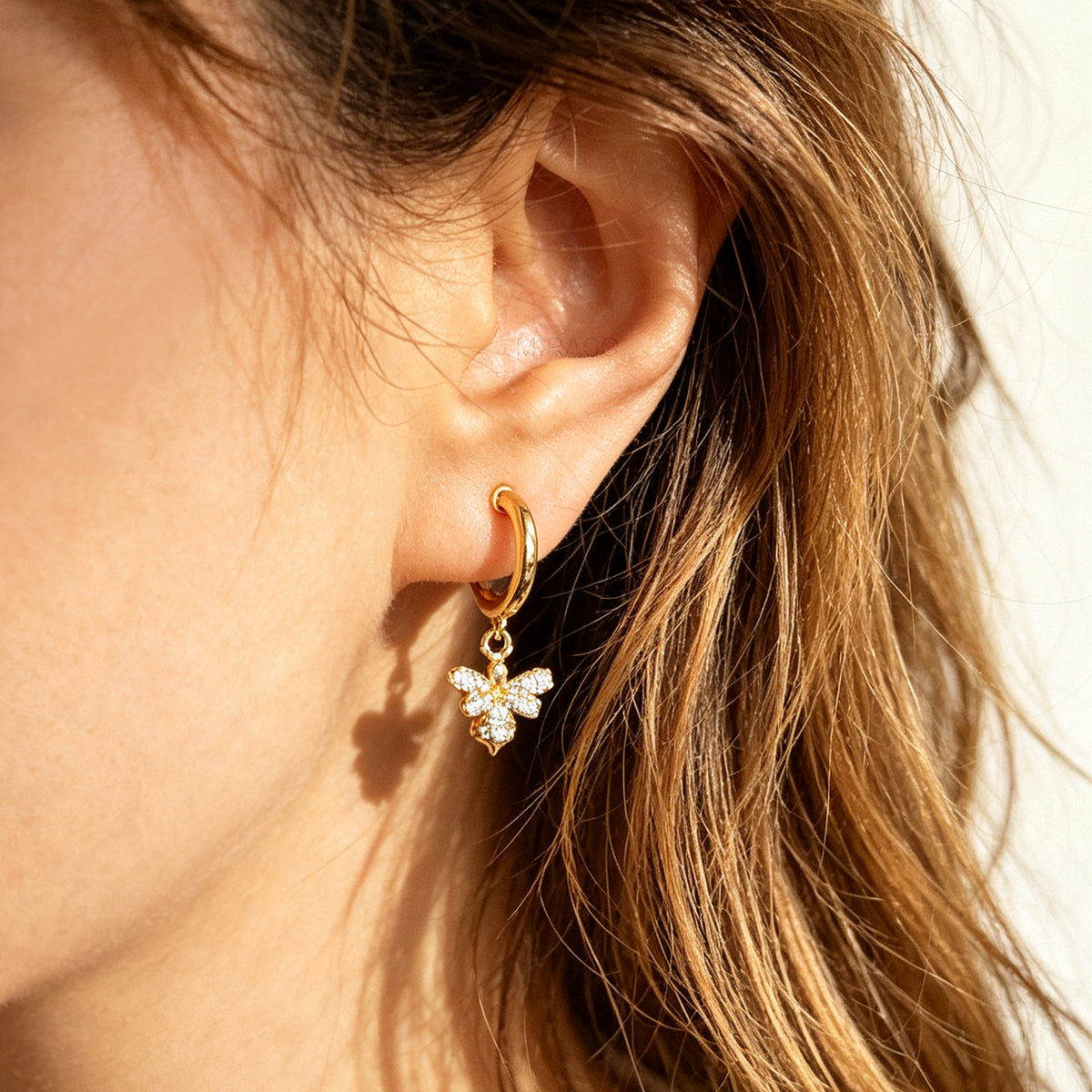Gold clip-on hoop earrings with a sparkling cubic zirconia pave bumblebee charm and comfortable round cushion backings.