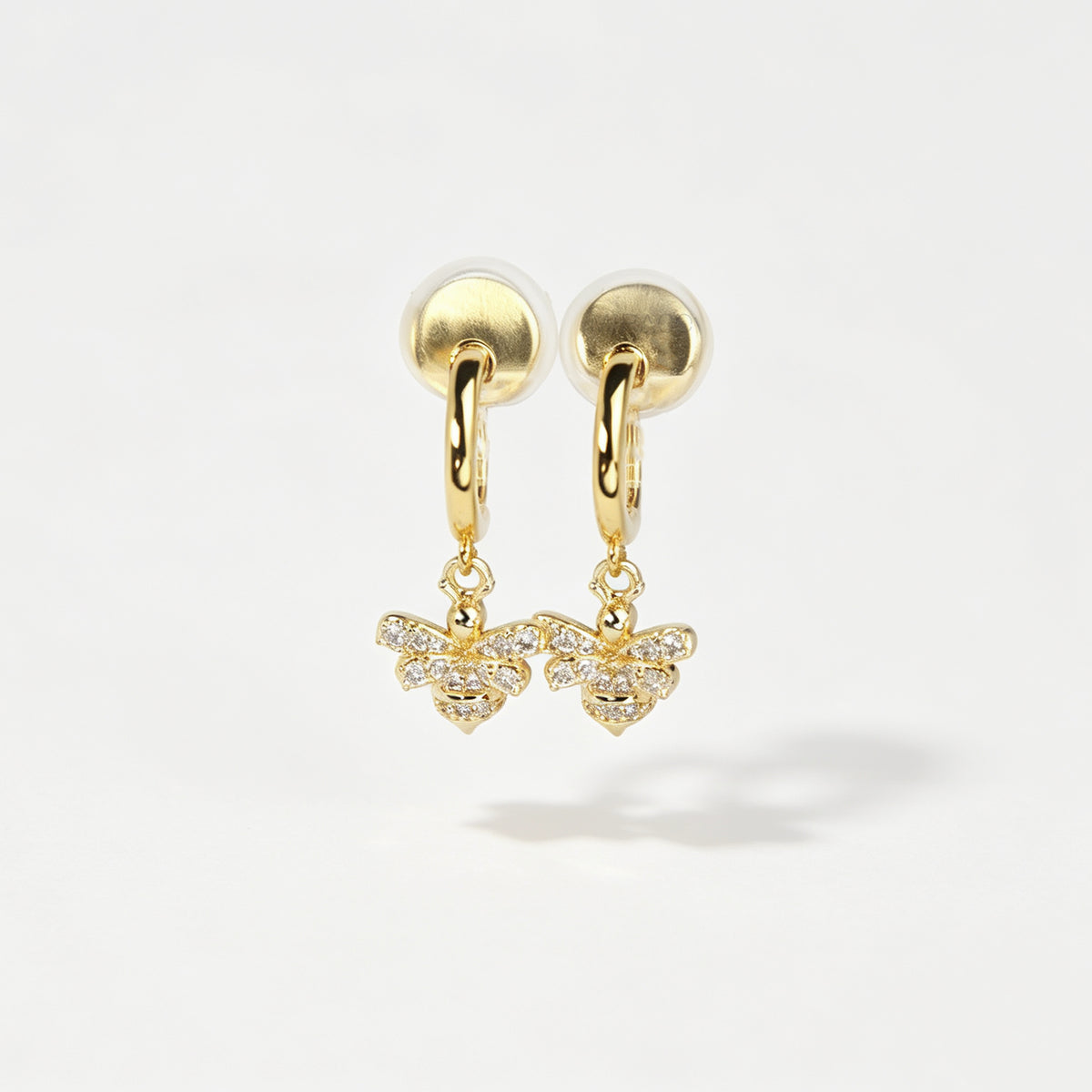 Gold clip-on hoop earrings with a sparkling cubic zirconia pave bumblebee charm and comfortable round cushion backings.