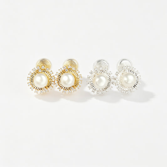 Gold and silver clip-on stud earrings featuring a central freshwater pearl framed by a pavé cubic zirconia sunburst halo with round cushioned coil backs.