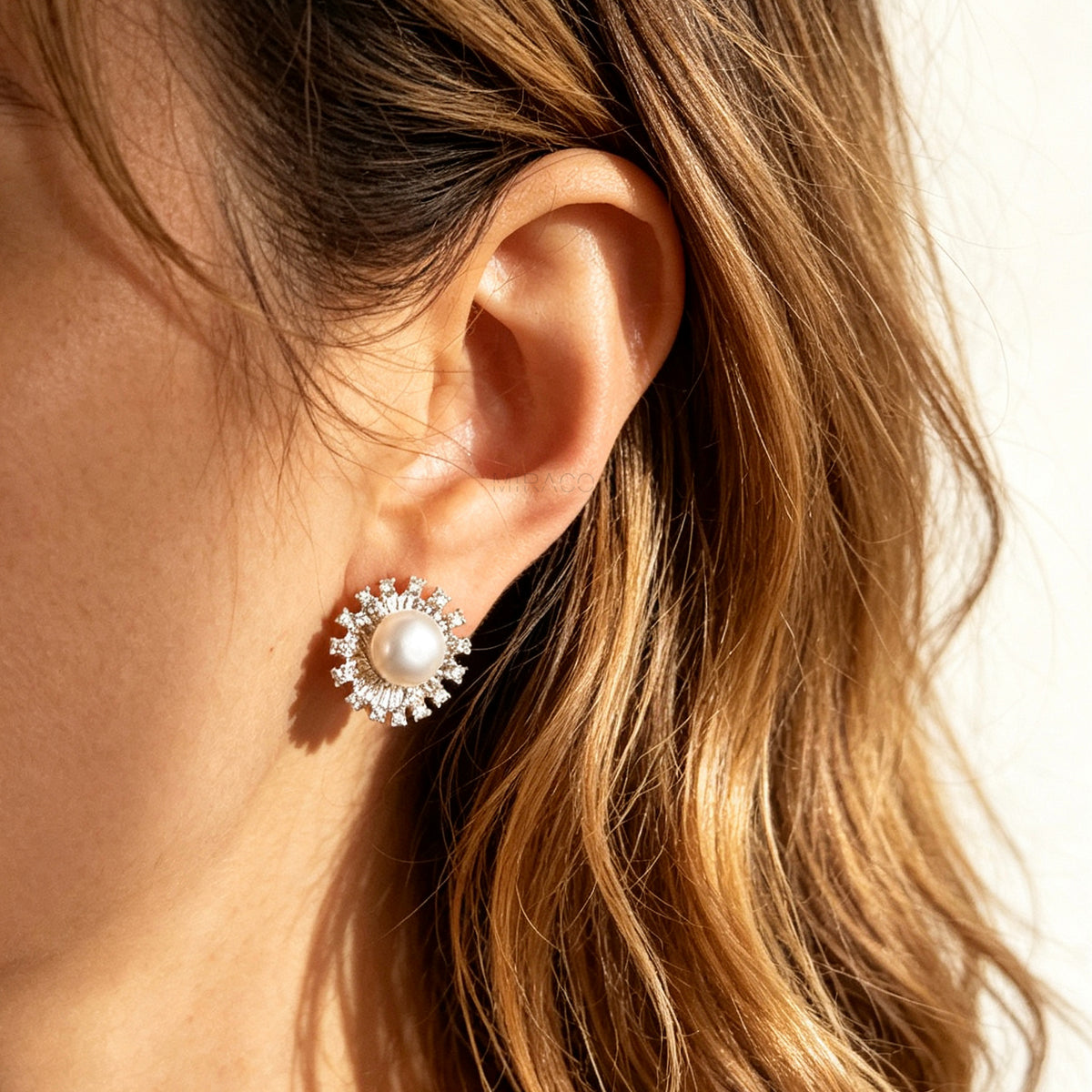Gold and silver clip-on stud earrings featuring a central freshwater pearl framed by a pavé cubic zirconia sunburst halo with round cushioned coil backs.