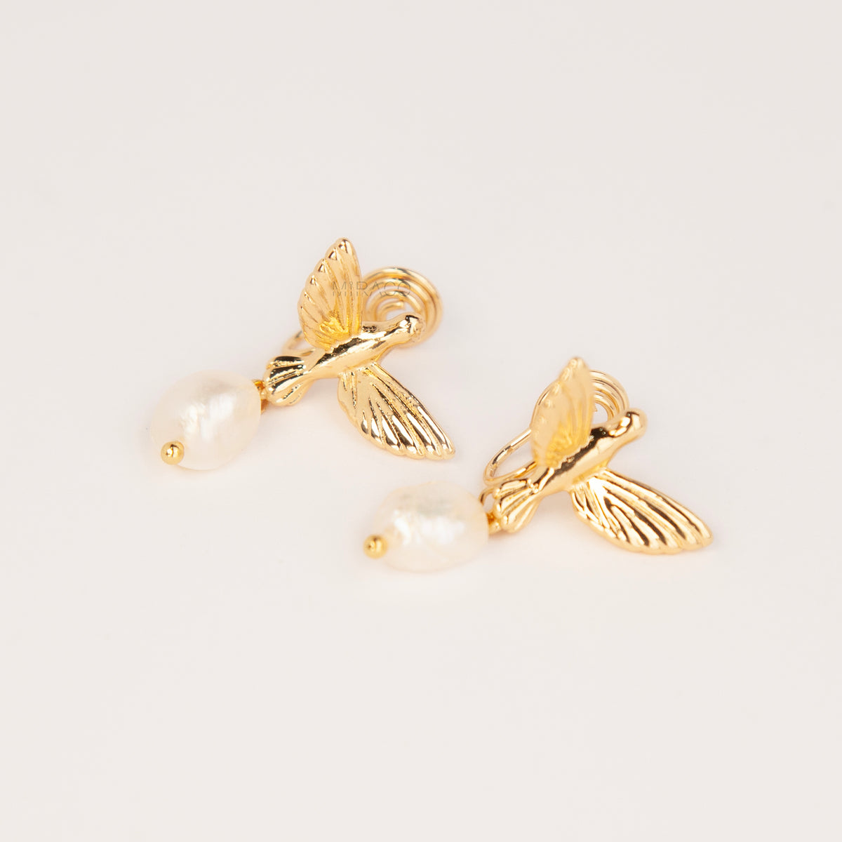 Gold and silver bird clip-on drop earrings featuring detailed flying bird motifs with dangling genuine freshwater baroque pearls on cushioned coil backs.