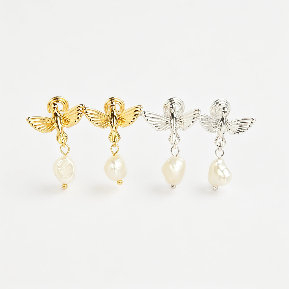 Gold and silver bird clip-on drop earrings featuring detailed flying bird motifs with dangling genuine freshwater baroque pearls on cushioned coil backs.