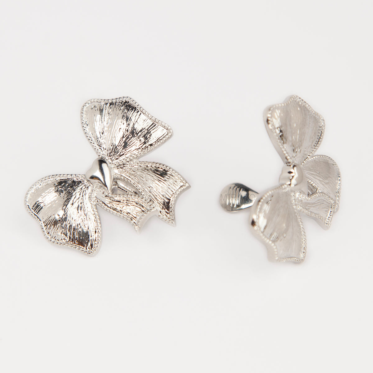 Woman wearing textured silver ribbon bow clip-on earring with a comfortable foldable paddle back for non-pierced ears.