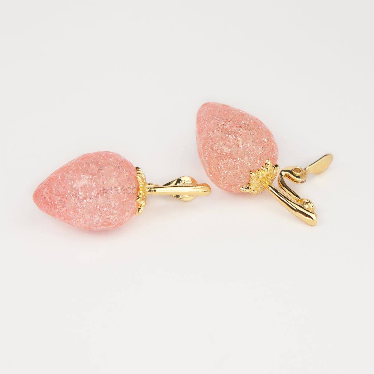 sparkling pink resin strawberry clip-on drop earring with a gold foldable paddle back for non-pierced ears.