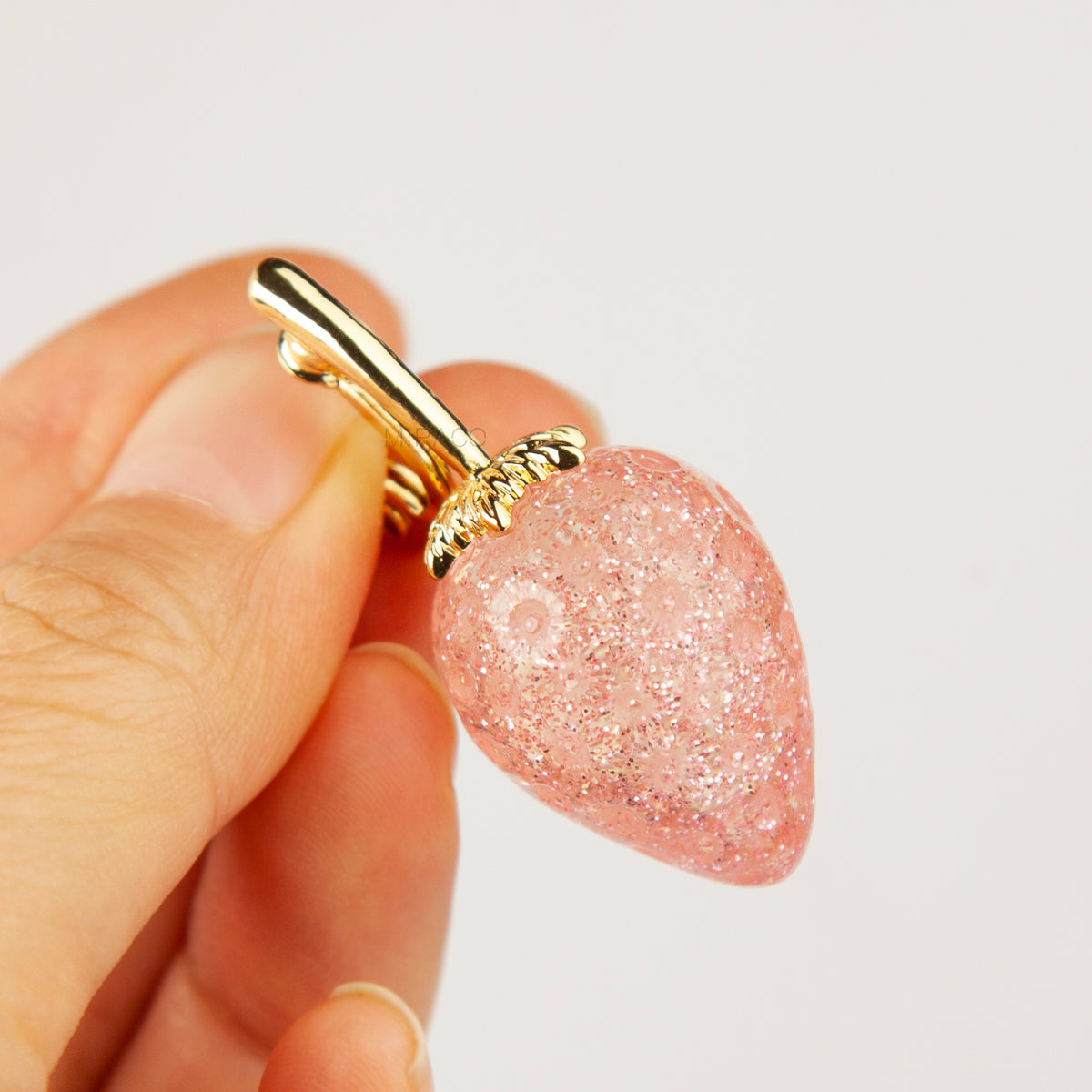 sparkling pink resin strawberry clip-on drop earring with a gold foldable paddle back for non-pierced ears.