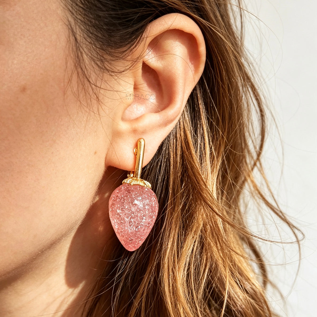 sparkling pink resin strawberry clip-on drop earring with a gold foldable paddle back for non-pierced ears.